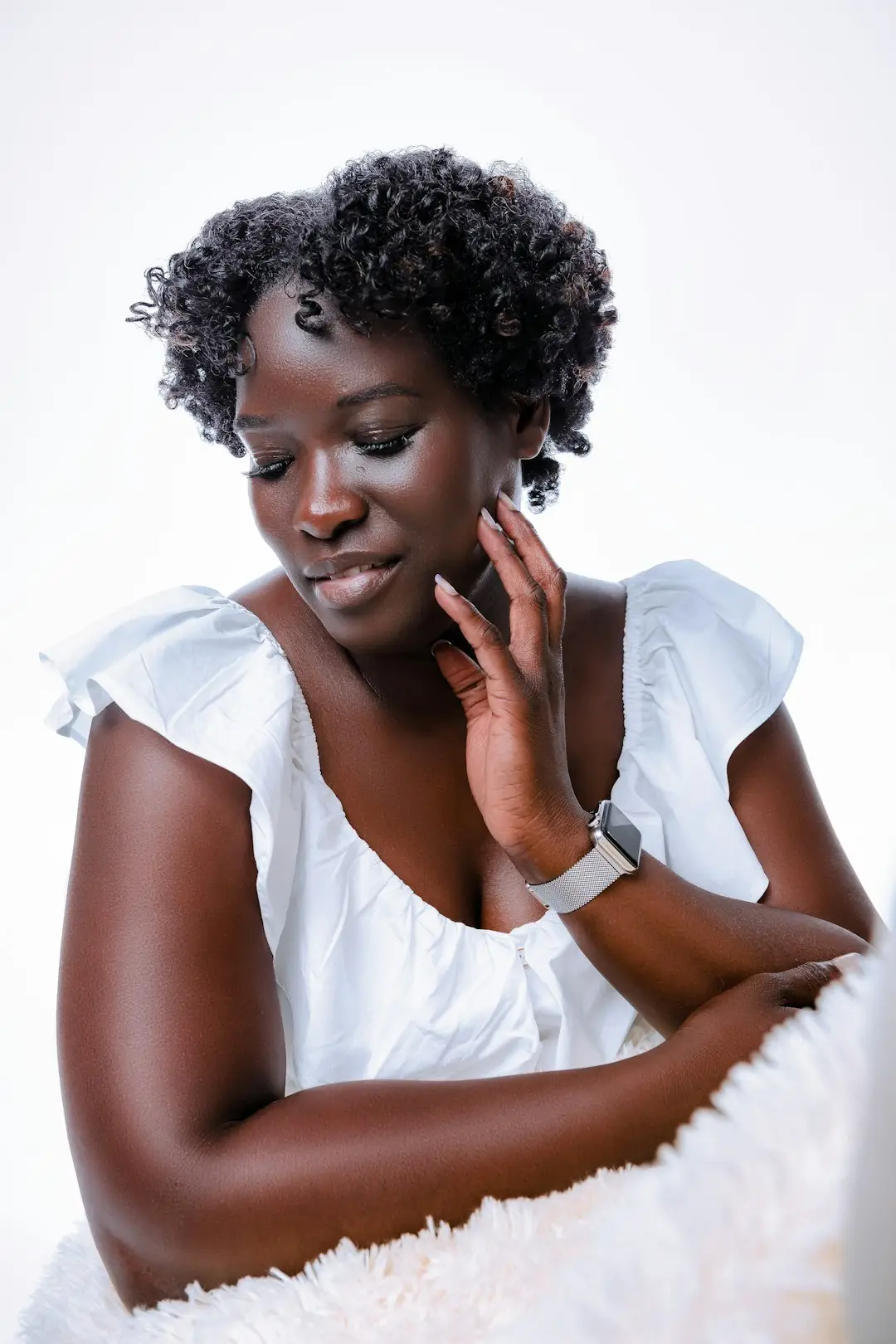 Mulher negra aplicando loção hidratante no braço, luz natural difusa