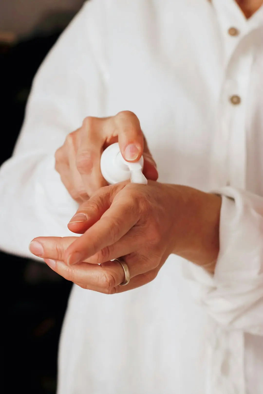 Mãos cuidadas aplicando creme, luz natural suave