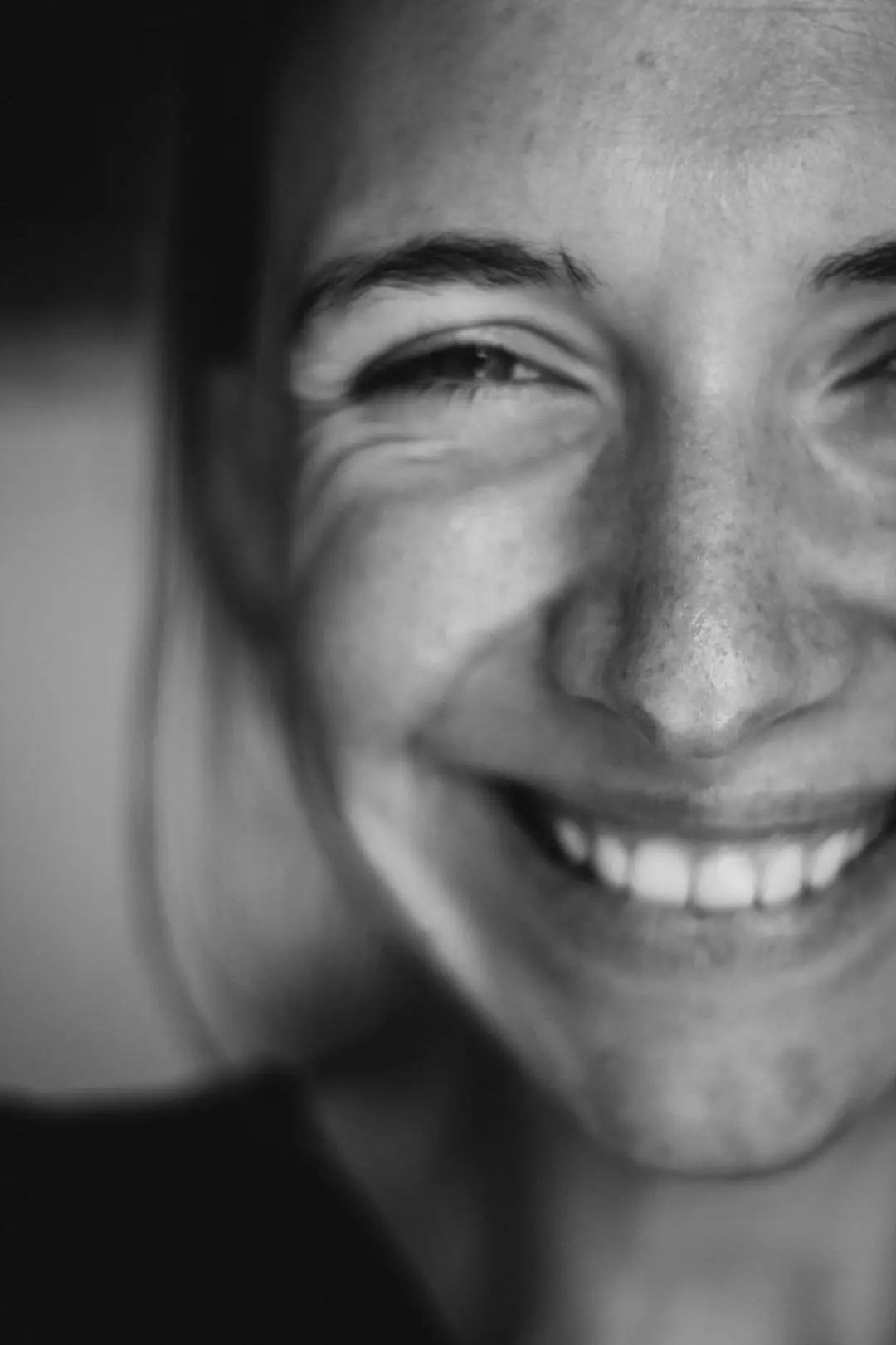 Retrato em luz natural de uma mulher madura sorrindo, com linhas de expressão visíveis no canto dos olhos