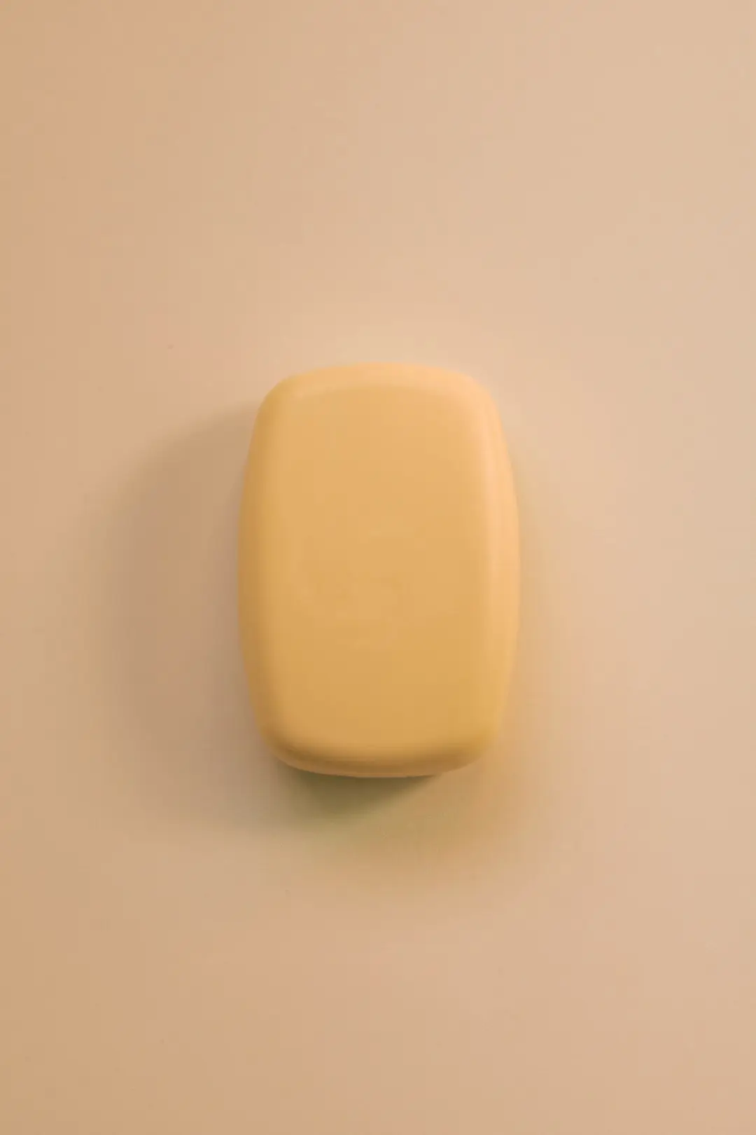 Um único stick de maquiagem cremoso sobre fundo bege, luz suave