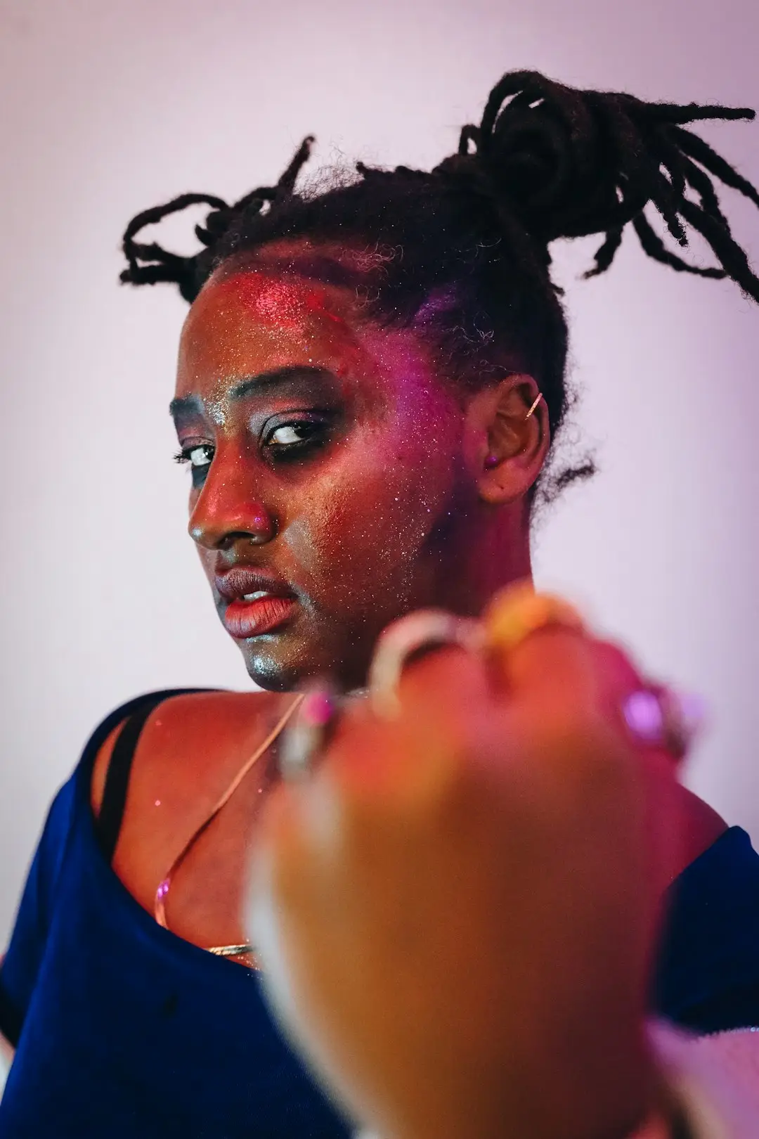 Mulher negra aplicando blush cremoso com os dedos, luz de manhã