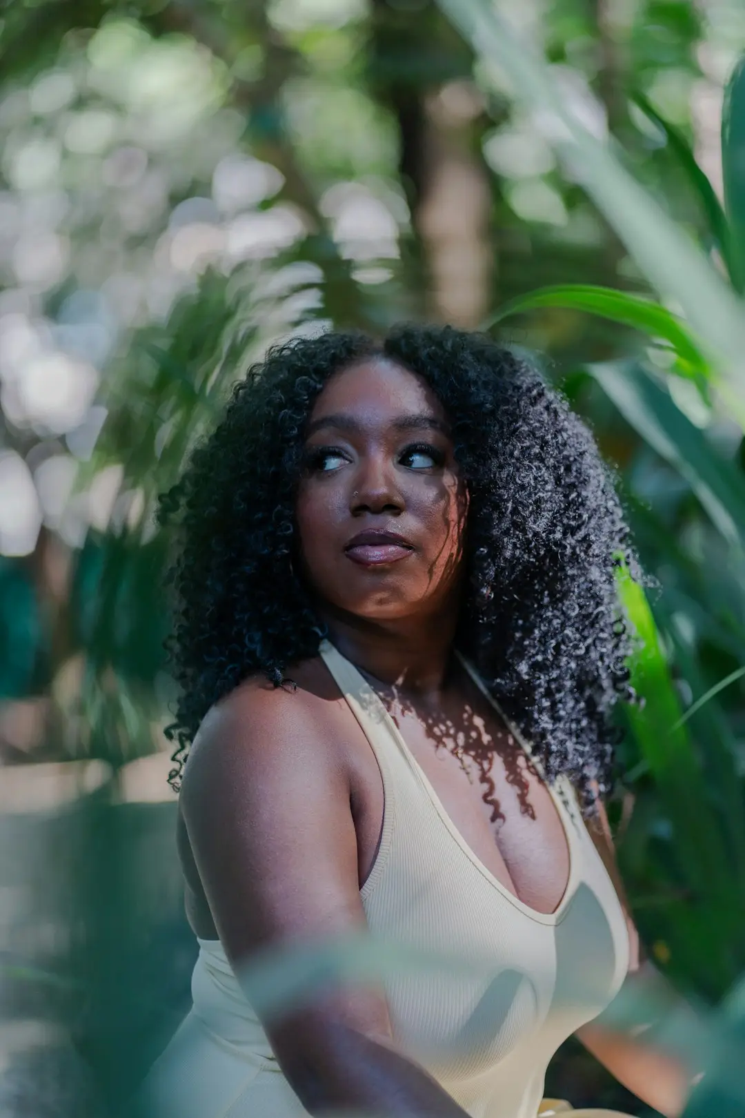 Mulher negra aplicando óleo nos cabelos cacheados antes da lavagem